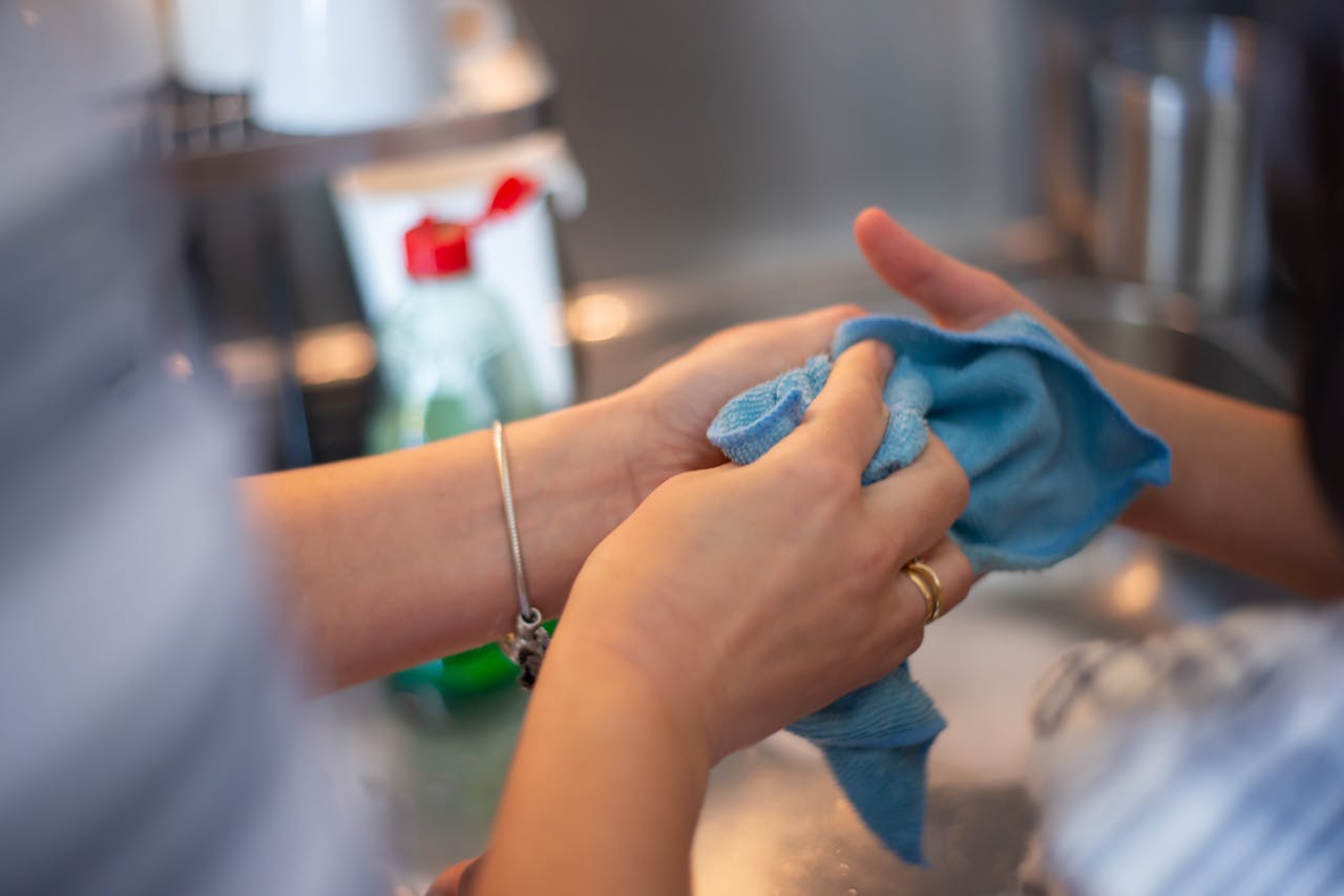 Detailed image of two people cleaning using a blue cloth indoors. Perfect for hygiene concepts.